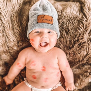 infant wearing gray heather beanie with personalized caramel patch and matte black rivets