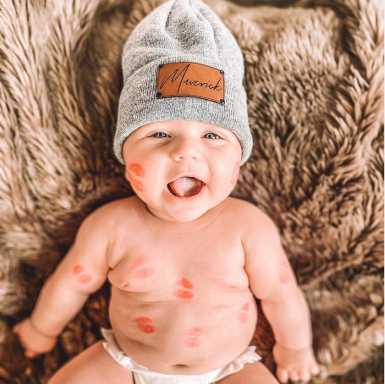 infant wearing gray heather beanie with personalized caramel patch and matte black rivets