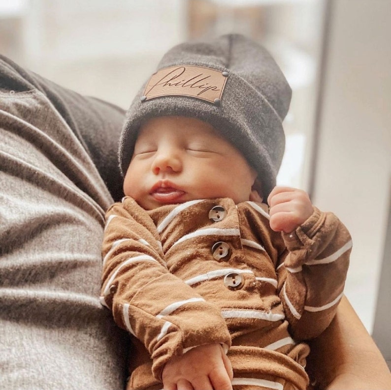 infant wearing charcoal heather beanie with personalized caramel patch and matte black rivets