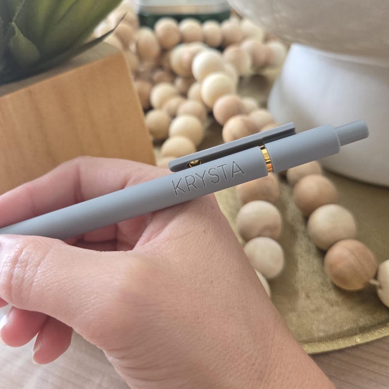 May include: A gray pen with a gold clip and the name "Krysta" engraved on the side.