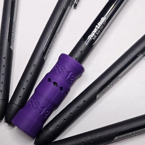 May include: Four black pens with purple grip, one pen has the text "Paper Mate Ink Joy gel 0.7" printed on the side.