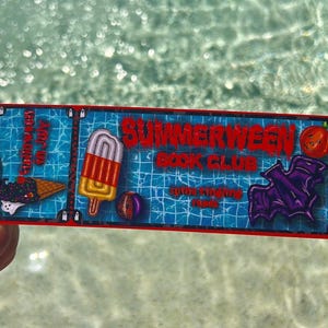 May include: A rectangular sticker with a blue swimming pool water background featuring the text Summerween Book Club. The design includes a black ice cream cone, a striped popsicle, a beach ball, a purple bat, and a small orange pumpkin icon.