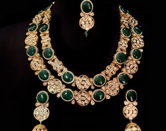 May include: A gold and green Indian bridal necklace set with large green stones and smaller white stones. The set includes a necklace, earrings, and a maang tikka.