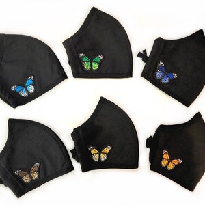 May include: Six black face masks with different colored butterfly embroidery. The butterflies are blue, green, yellow, orange, brown, and blue.
