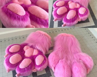 Puede incluir: Almohadillas de pata de piel sintética rosa y magenta con almohadillas rosas claras. Las patas están hechas de un material suave y esponjoso y están diseñadas para parecerse a patas de animales. La imagen muestra múltiples vistas de las patas.