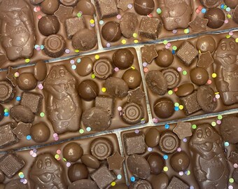 May include: Milk chocolate bars topped with Freddo frog-shaped chocolates, square chocolate pieces, round chocolate buttons, and colorful sprinkles. Each bar features a molded character with the text Freddo embossed on the front surface.