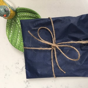 Puede incluir: Un regalo azul marino envuelto en papel de seda y atado con cuerda.
