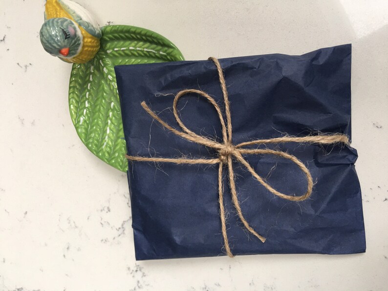 Puede incluir: Un regalo azul marino envuelto en papel de seda y atado con cuerda.