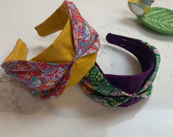 May include: Two fabric headbands, one with a yellow and floral pattern and the other with a purple and green floral pattern.