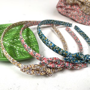 May include: Four floral patterned headbands with knotted ends. The headbands are in shades of blue, pink, and yellow.