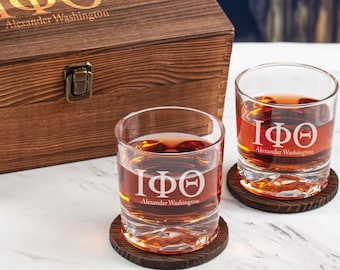 May include: Two engraved whiskey glasses with the letters "IΦΘ" and the text "Alexander Washington" on a wooden coaster. The glasses are in front of a wooden box with the same engraving.