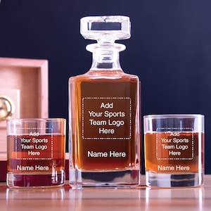 May include: A set of three clear glass decanters with a square base and a stopper. The decanters are filled with a dark amber liquid. The decanters have a personalized label that says "Add Your Sports Team Logo Here" and "Name Here".
