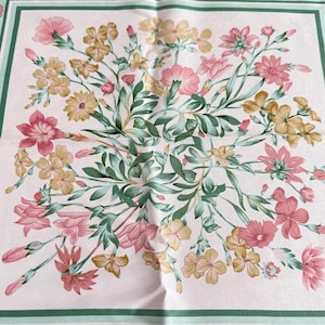 May include: A square scarf featuring a pale pink background with a central floral arrangement of pink and yellow flowers, green leaves, and stems. The design is framed by a double border in shades of dark and light green, creating a structured look.