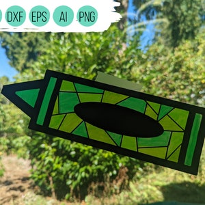 May include: A green crayon with a stained glass design. The crayon is outlined in black and has a black label.
