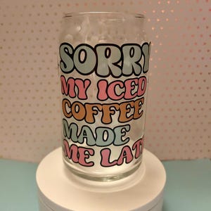 Puede incluir: Una taza de vidrio con un diseño colorido que dice "Lo siento, mi café helado me hizo llegar tarde".