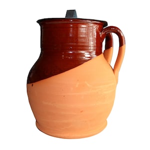 Puede incluir: Una jarra de cerámica marrón y naranja con asa. La jarra tiene una parte superior marrón oscura y una parte inferior naranja más clara.