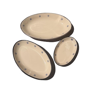 Puede incluir: Tres fuentes ovaladas. Las fuentes tienen un interior color crema y un borde oscuro. Pequeños diseños florales azules están espaciados uniformemente alrededor del borde. Las fuentes son de diferentes tamaños.