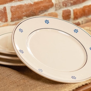 Puede incluir: Un conjunto de cuatro platos de cerámica blanca con un diseño floral azul alrededor del borde.