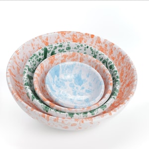 Puede incluir: Conjunto de cuatro cuencos encajables con base blanca y diseño moteado en tonos naranja, verde y azul.