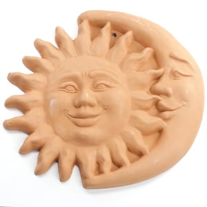 Peut inclure: Décoration murale en terre cuite représentant le soleil et la lune avec des visages souriants. Le soleil a des rayons et la lune est en forme de croissant.
