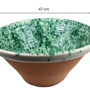 Puede incluir: Un cuenco grande de cerámica verde y blanco con un esmalte moteado. El cuenco tiene 47 cm de diámetro y una base de terracota.