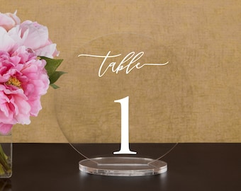 May include: Clear acrylic table number holder with the word "table" and the number "1" in white lettering.