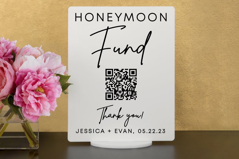 May include: White sign with black text that reads "Honeymoon Fund" with a black and white QR code and the text "Thank you!"  Below the QR code is the text "Jessica + Evan, 05.22.23"