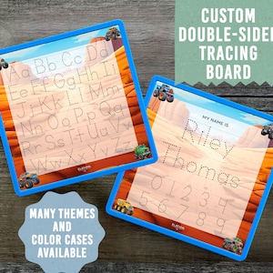 May include: Double-sided tracing board with a monster truck theme. One side features the alphabet and the other side has a name space, "My name is", and numbers 0-9. The board has a blue frame and a desert-like background.