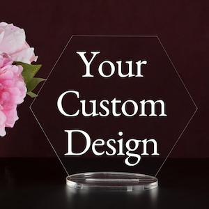 May include: A clear acrylic hexagonal sign with a white stand. The sign says "Your Custom Design".