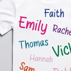 May include: White t-shirt featuring a selection of names in various colours and fonts. Names include Emily, Faith, Thomas, Vicky, Rachel, Hannah, Sam, and Bobby. The names are printed across the front.