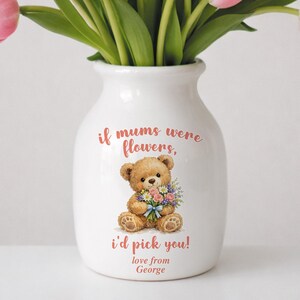 May include: White ceramic vase with a teddy bear illustration holding flowers, and the text "if mums were flowers, I'd pick you! love from George." The vase holds a bouquet of pink tulips with green stems.
