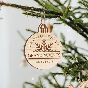 May include: Wooden Christmas ornament shaped like a bauble with the text "Promoted to Grandparents Est. 2024" and a snowflake design.