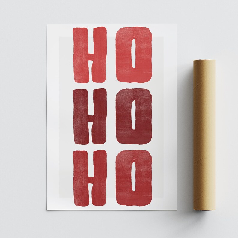 May include: A rectangular print with the words "HO HO HO" in red, block letters. The print is on white paper, and a rolled-up brown poster is next to it. The letters have a textured, painted appearance.