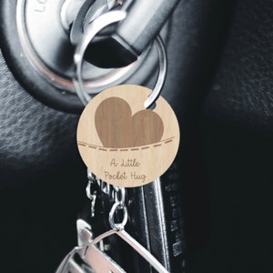May include: A wooden keychain with a heart shape and the text "A Little Pocket Hug".
