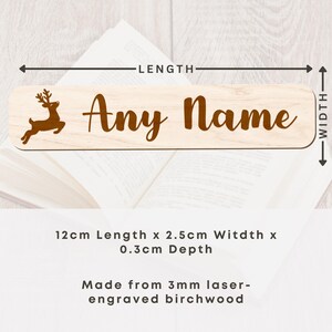 May include: A light-colored wooden nameplate with the text "Any Name" in a brown script font. A brown reindeer silhouette is on the left. The nameplate is 4.7 inches long, 1 inch wide, and 0.1 inches deep. Made from laser-engraved birchwood.