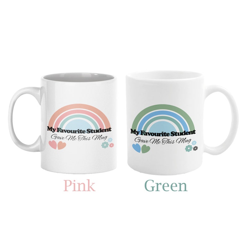 May include: Two white ceramic mugs with a rainbow design and the text "My Favourite Student Gave Me This Mug". The mug on the left has a pink rainbow and the mug on the right has a green rainbow. The text "Pink" is below the left mug and the text "Green" is below the right mug.