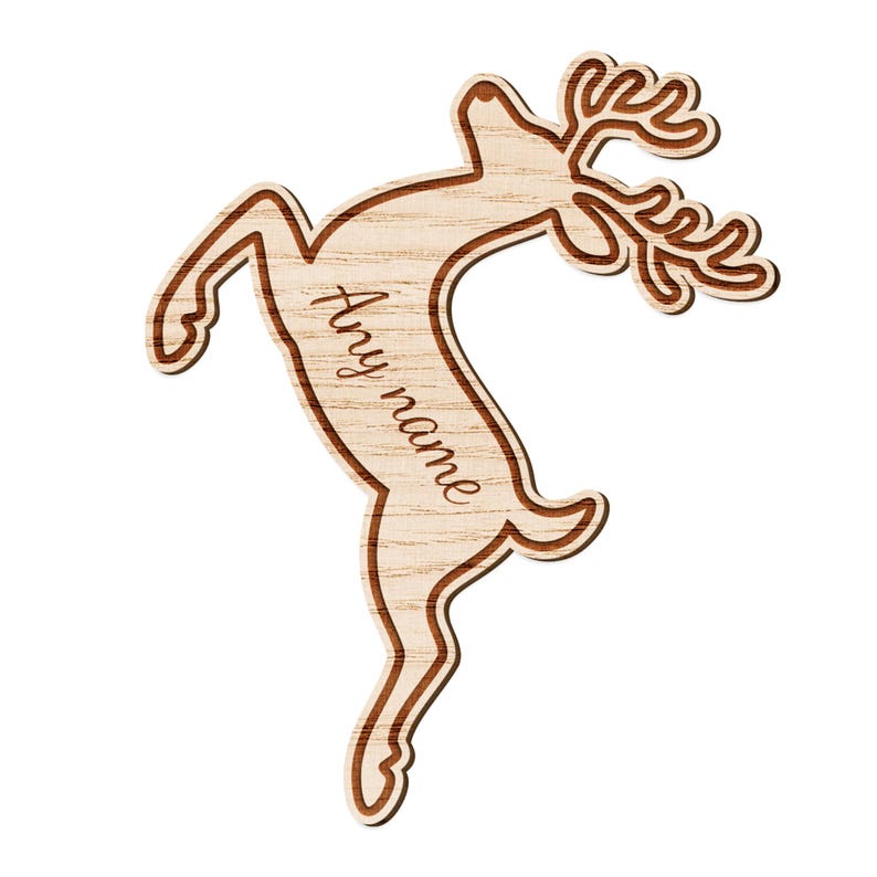 May include: A wooden reindeer ornament with a light brown body and darker brown outline. The reindeer is leaping with its head up and antlers displayed. The text "Any name" is written on the body of the reindeer.