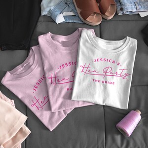 May include: Three pink and white t-shirts with the text "Jessica's Hen Party" and "The Bride" printed in pink on the front.