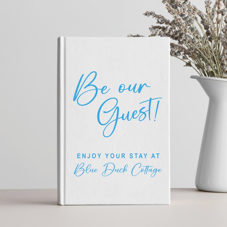 Pu&ograve; includere: Libro bianco con testo blu che dice "Be our Guest!" e "Enjoy your stay at Blue Duck Cottage".