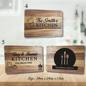 May include: Three wooden cutting boards with personalized text. The first board says "The Smith's Kitchen" with a chef's hat graphic. The second board says "Tracy & Rowan's Kitchen" with a red apple graphic and the date "25th March 2022". The third board says "The William's Kitchen" with a fork, knife, and spoon graphic. The boards are 34 cm x 24 cm x 1.5 cm.