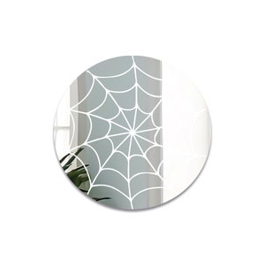 May include: A round mirror with a white spiderweb design on a gray background.