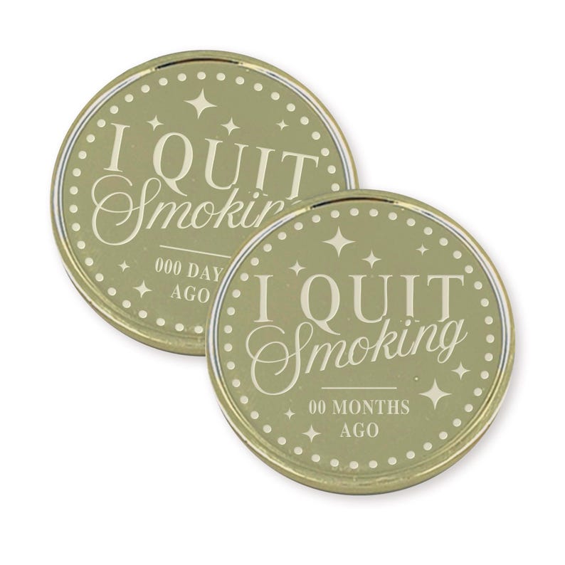 May include: Two round, olive-green coins with gold rims. The text "I QUIT Smoking" is centered on each coin. One coin reads "000 DAY AGO" and the other reads "00 MONTHS AGO". Each coin has a dotted border and star accents.