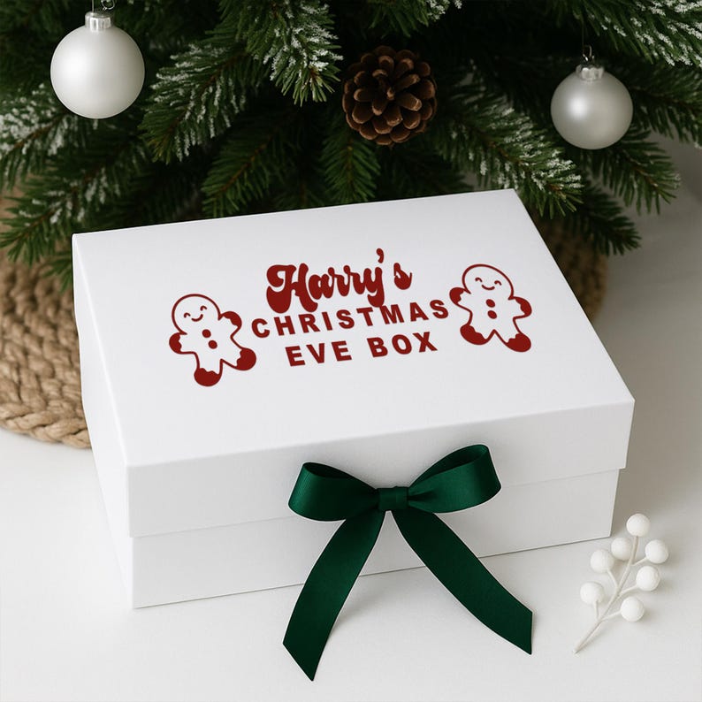 May include: A white Christmas Eve box tied with a dark green bow. The box features the text "Harry's CHRISTMAS EVE BOX" in red, and two gingerbread man graphics. The box is decorated with Christmas ornaments and a pine cone.