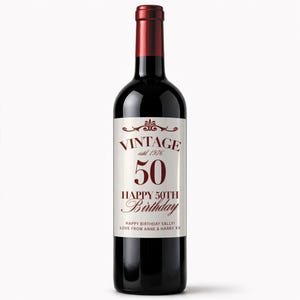 May include: A dark red wine bottle with a white label. The label reads "VINTAGE estd 1976 50 HAPPY 50TH BIRTHDAY" in burgundy lettering. The bottle is a birthday gift with a personalized message.