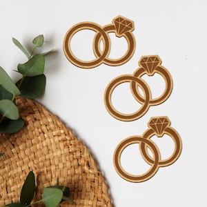 May include: Three sets of wooden ring napkin rings with a diamond design. The rings are brown and the diamonds are a lighter brown.