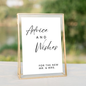 May include: A gold-framed sign with white paper inside. The sign says "Advice and Wishes for the New Mr. & Mrs."