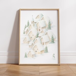 May include: Watercolour print of a snow-covered village with houses, a church, and evergreen trees. The artwork features a snowman and a soft colour palette of white, beige, and green, framed in a light wood.