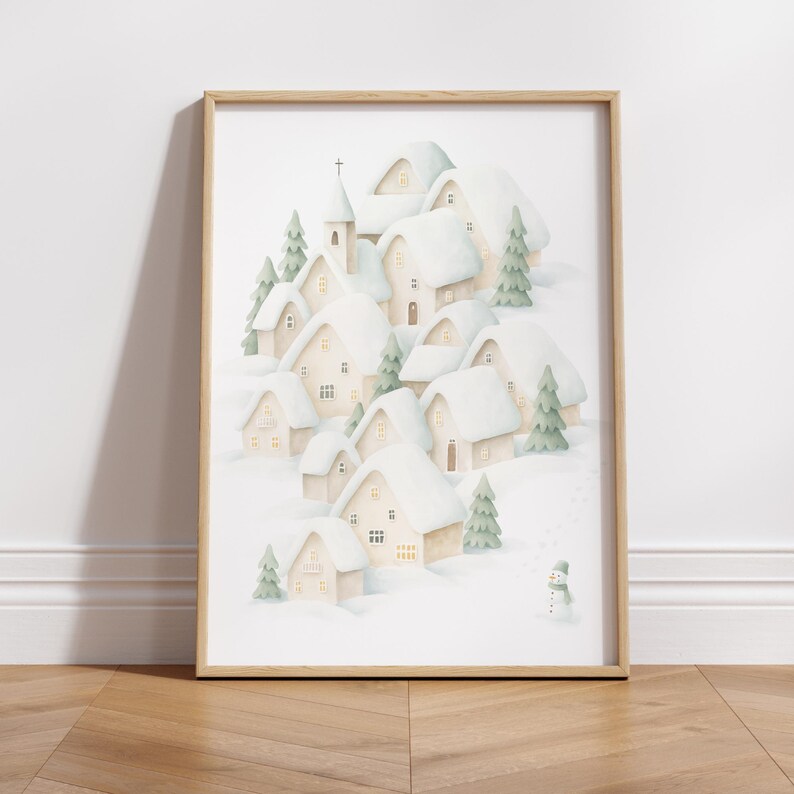 May include: Watercolour print of a snow-covered village with houses, a church, and evergreen trees. The artwork features a snowman and a soft colour palette of white, beige, and green, framed in a light wood.