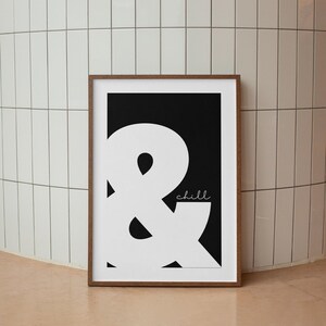 May include: A black and white print with a large white ampersand symbol and the word "chill" in white text on a black background. The print is framed in a brown wood frame.