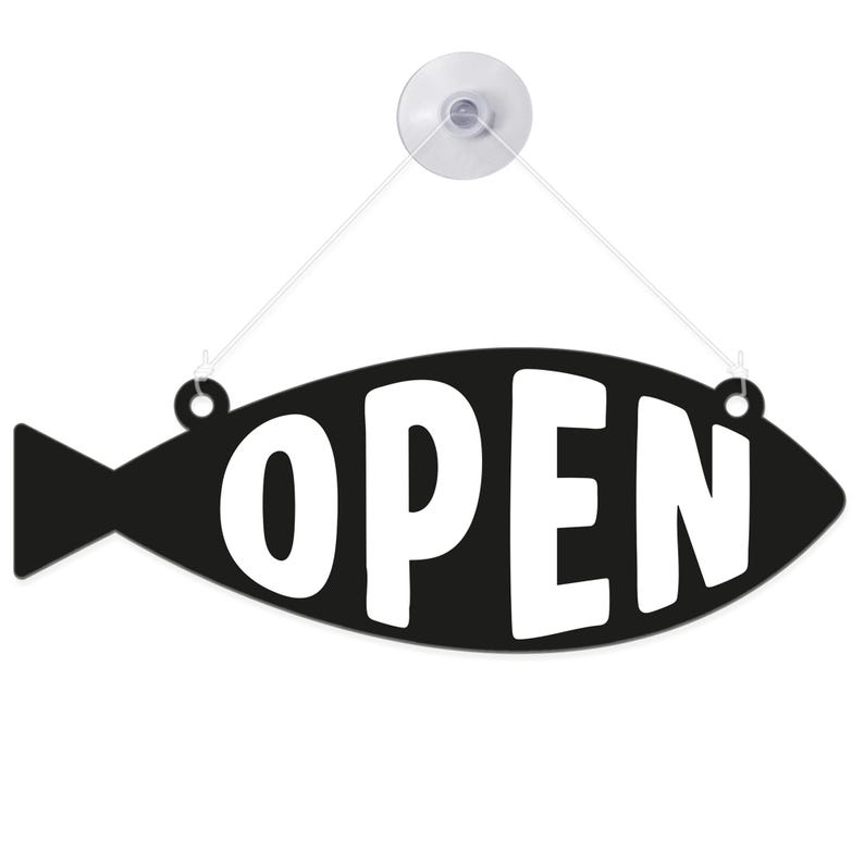 May include: Black fish-shaped sign with the word "OPEN" in white. The sign is suspended by a clear suction cup and string. The sign is designed to be hung on a window or door to indicate a business is open.
